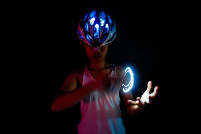 Man wearing illuminated cycling helmet against black background