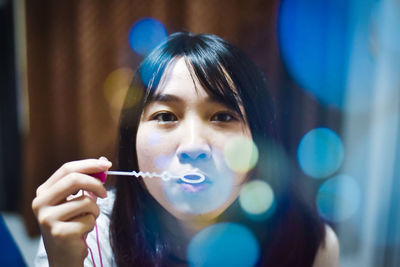 Young woman blowing bubbles at home