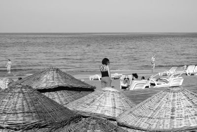 Woman sitting on beach against clear sky in kyrenia