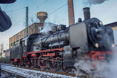 Steam train on railroad tracks against sky