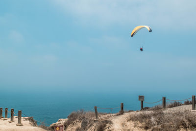 Person paragliding against sea and sky