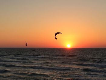 Silhouette person in sea against sky during sunset