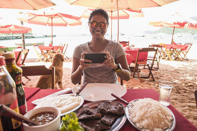 Woman at beach restaurant taking picture of food