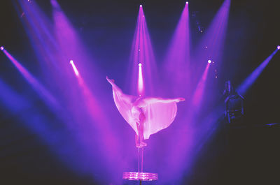 Woman dancing on illuminated stage at night