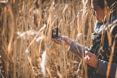 Close-up of woman hand on grass in field