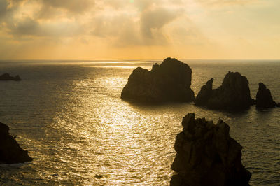 Rocks on sea against sky during sunset