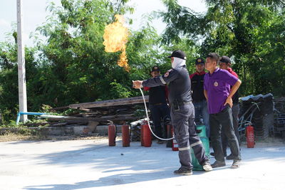 Rear view of people standing against trees