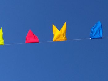 Low angle view of flags against clear blue sky