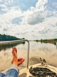 Low section of person in lake against sky