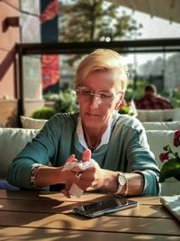 Portrait of woman holding camera while sitting on table