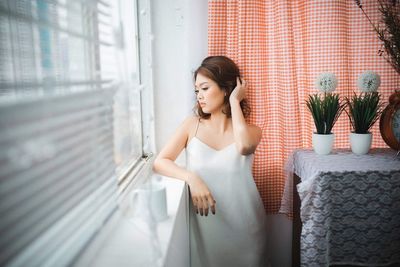 Woman looking away while standing on window
