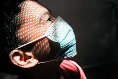 Close-up of boy wearing mask against black background