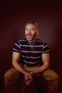 Portrait of man sitting against black background