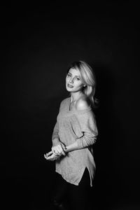 Portrait of woman standing against black background