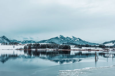 Scenic view of lake by snowcapped mountains against sky