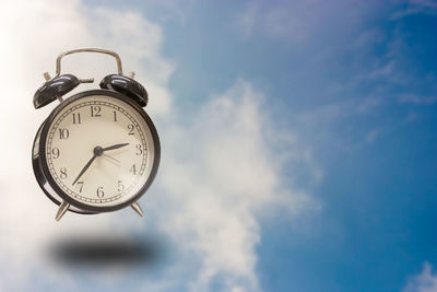 Low angle view of clock against sky