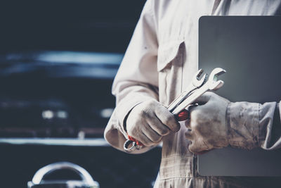 Mechanic holding work tools in garage