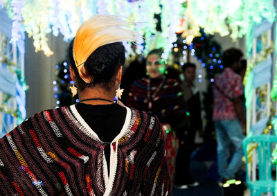 Rear view of man standing against multi colored umbrella