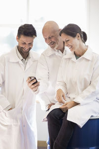 Happy technicians using mobile phone in manufacturing plant