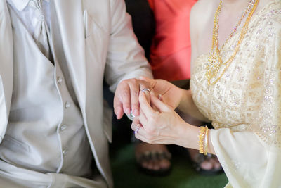 Midsection of wedding couple exchanging finger rings during ceremony