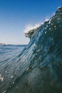 Waves in sea against clear blue sky