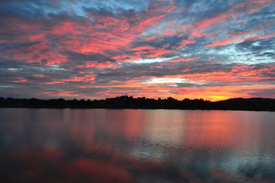 Scenic view of lake against dramatic sky during sunset