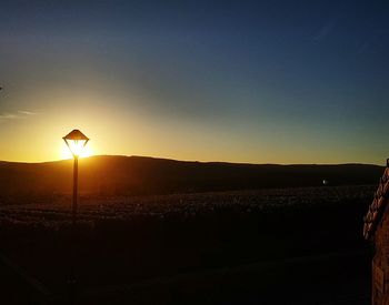 Scenic view of silhouette field against clear sky during sunset