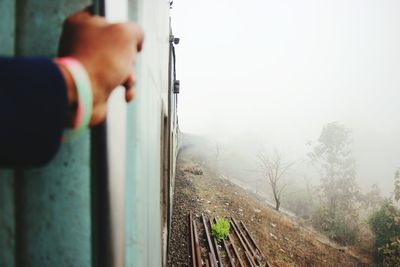 Close-up of human hand holding handle in train during foggy weather