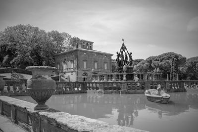 Statue by lake against sky