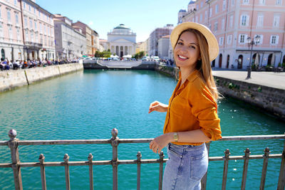 Traveler girl standing on the bridge with beautiful view of trieste city, italy