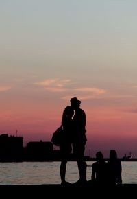 Silhouette people on beach against sky during sunset