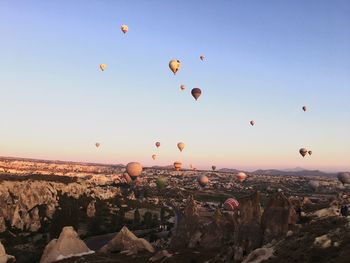 Hot air balloons flying over dramatic landscape against blue sky