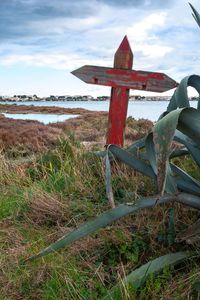 Rusty metallic structure on field by sea against sky