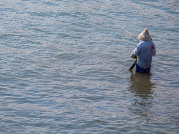 Rear view of man fishing in sea