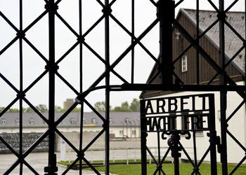 Metal gate against sky seen through chainlink fence