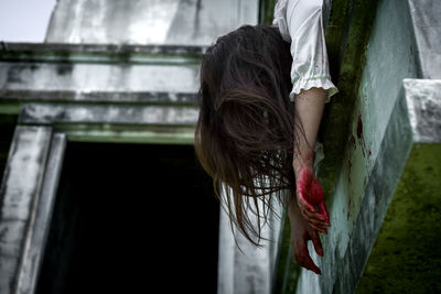 Low angle view of woman hanging on building wall during halloween