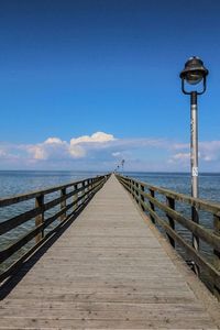 Pier over sea against clear blue sky
