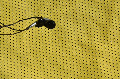 Full frame shot yellow textile with in-ear headphones