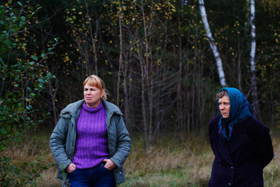 Two woman standing in pine forest. leisure and people concept, mother and daughter in fall forest. 