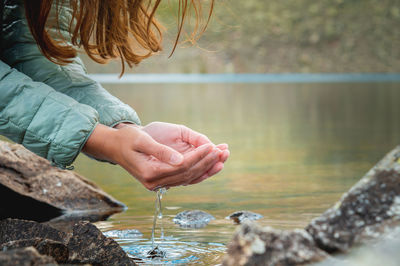 Close-up, hands of a girl drinking water from a stream or lake in the mountains. tourist quenches