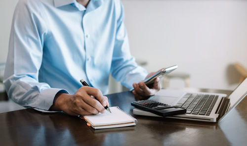 Midsection of man using mobile phone on table