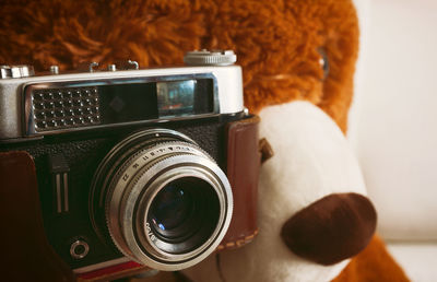 Teddy bear stuffed toy taking photo with retro camera.