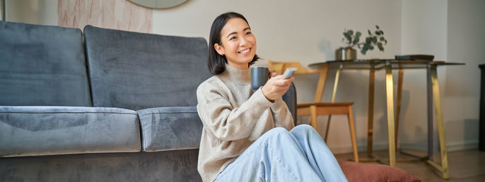 Portrait of young woman sitting on sofa at home