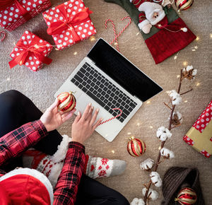 Directly above shot of young woman using laptop by christmas decoration