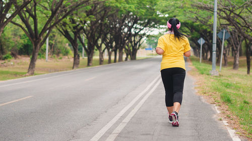 Rear view of woman running on road