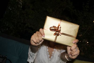 Woman covering face with gift box at night