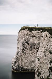 Close-up of cliff by sea against sky