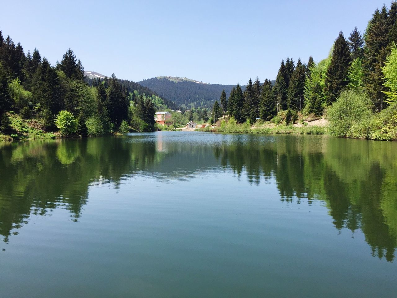 water, lake, reflection, tree, tranquil scene, mountain, tranquility, clear sky, waterfront, scenics, beauty in nature, nature, idyllic, mountain range, calm, river, standing water, blue, sky, day