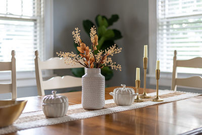 Dining room table with stylish fall decorations in white and gold