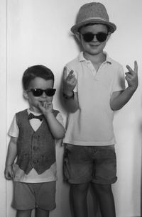 Boy wearing sunglasses standing against wall